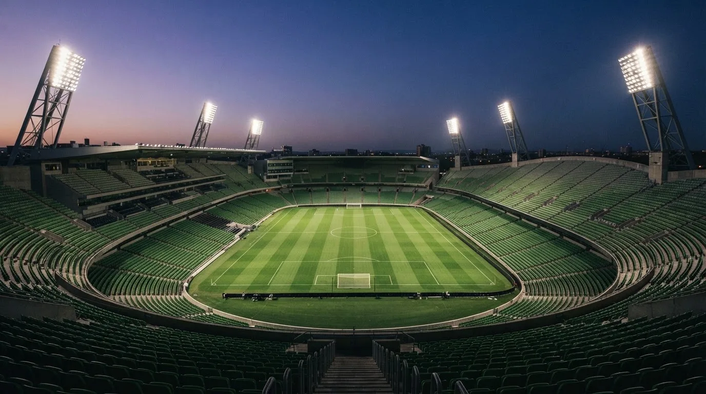 Een leeg voetbalstadion met lichtmasten bij schemering