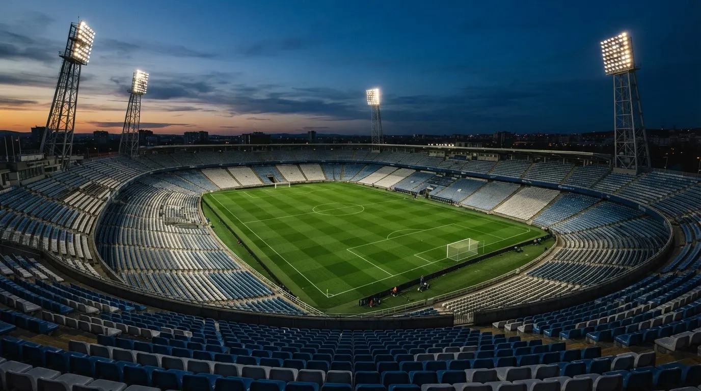 Een leeg voetbalstadion met lichtmasten bij schemering