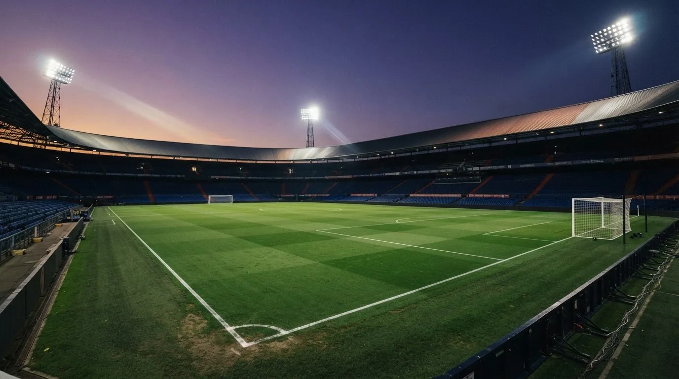 Een leeg voetbalstadion met lichtmasten bij schemering