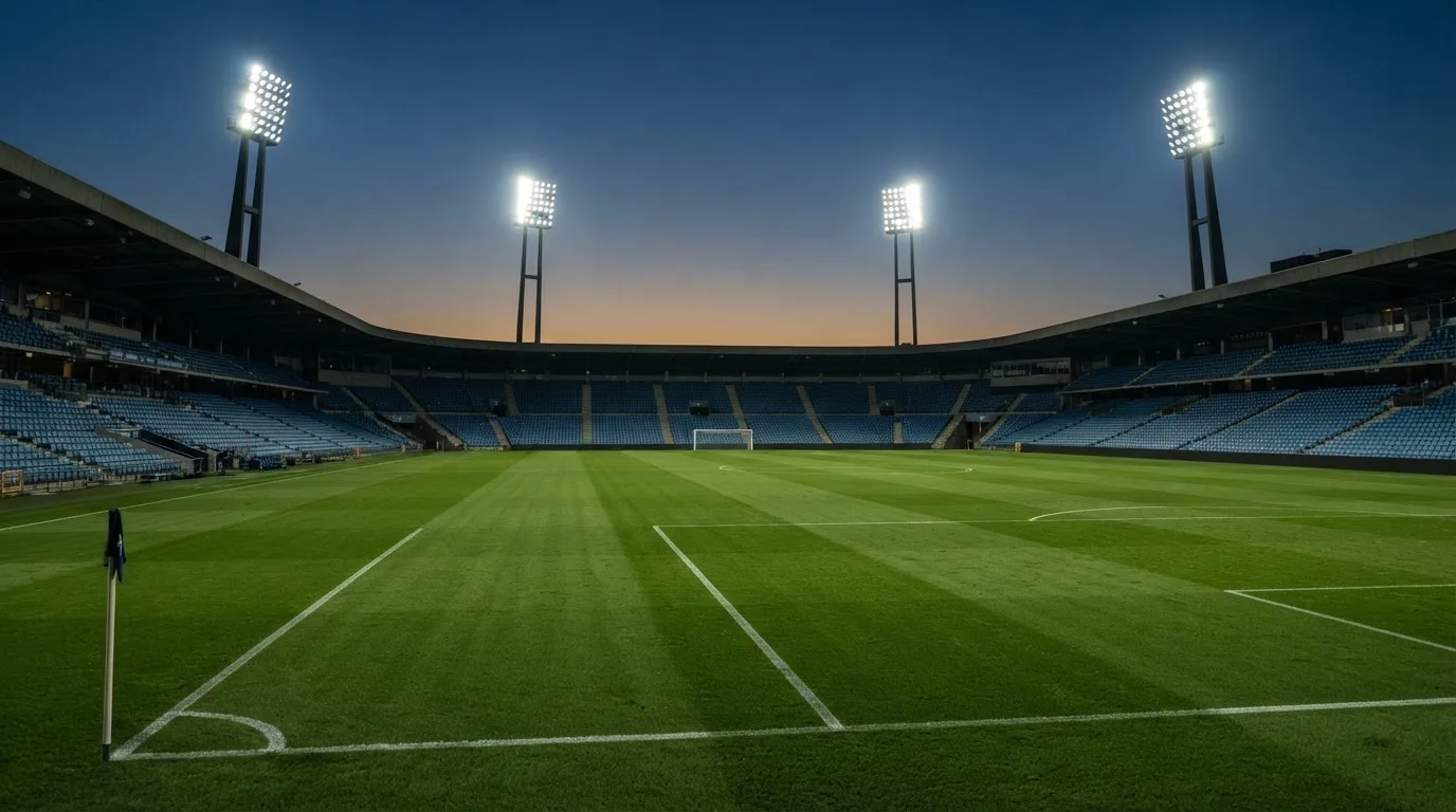 Een leeg voetbalstadion met lichtmasten bij schemering