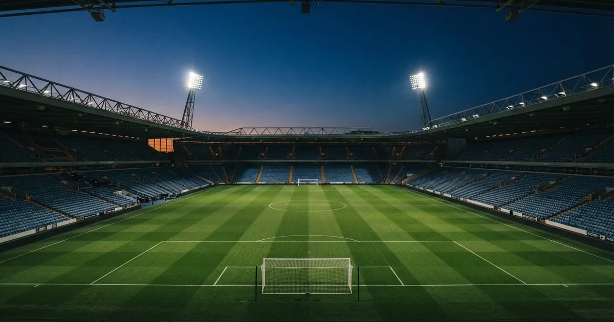 Een leeg voetbalstadion met lichtmasten bij schemering