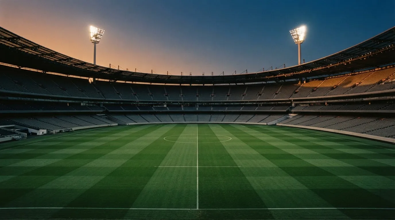 Een leeg voetbalstadion met lichtmasten bij schemering
