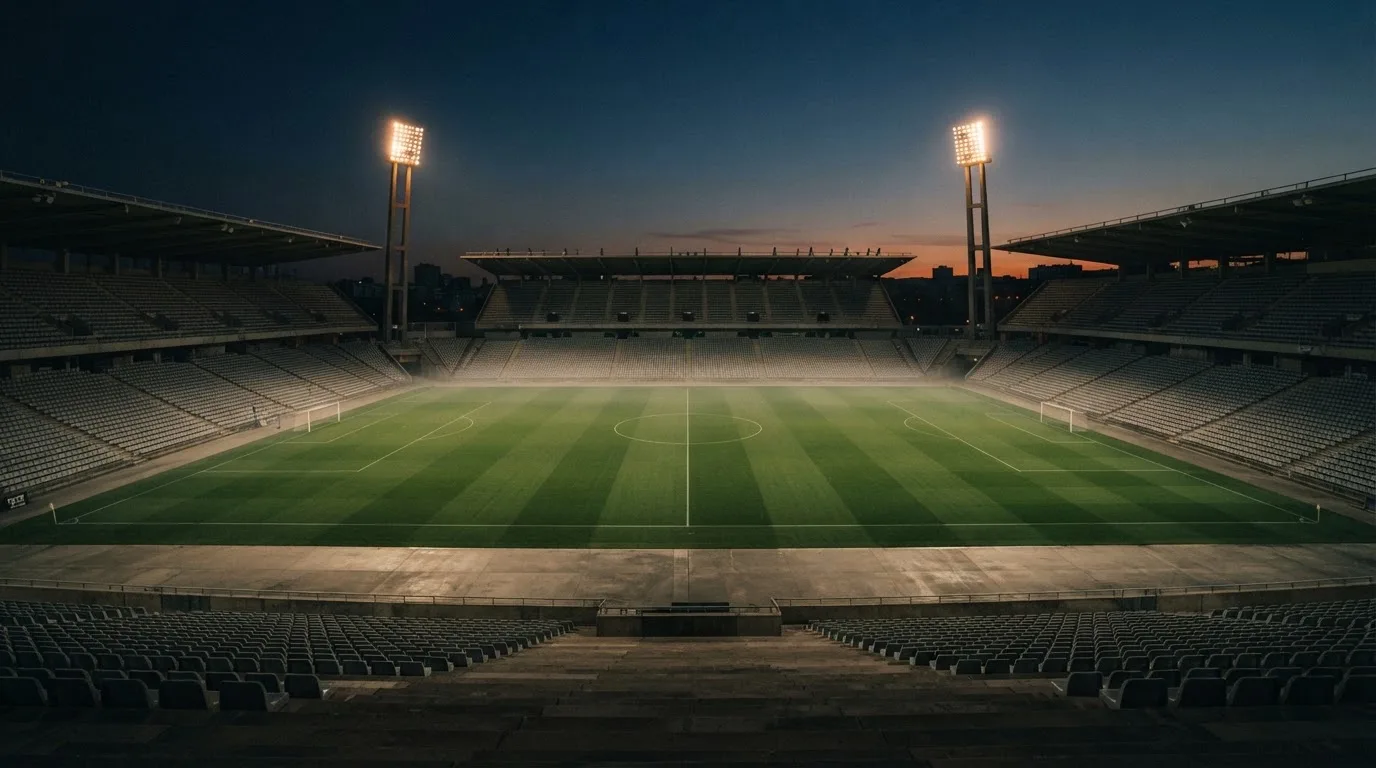 Een leeg voetbalstadion met lichtmasten bij schemering