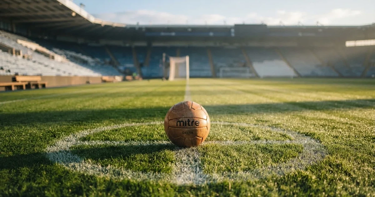 Een voetbal op de middenstip van een grasveld in het ochtendlicht