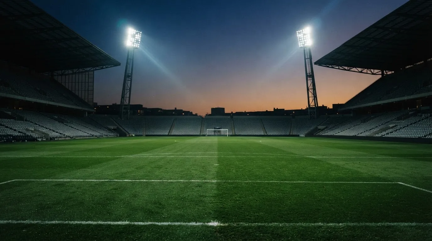 Een leeg voetbalstadion met lichtmasten bij schemering