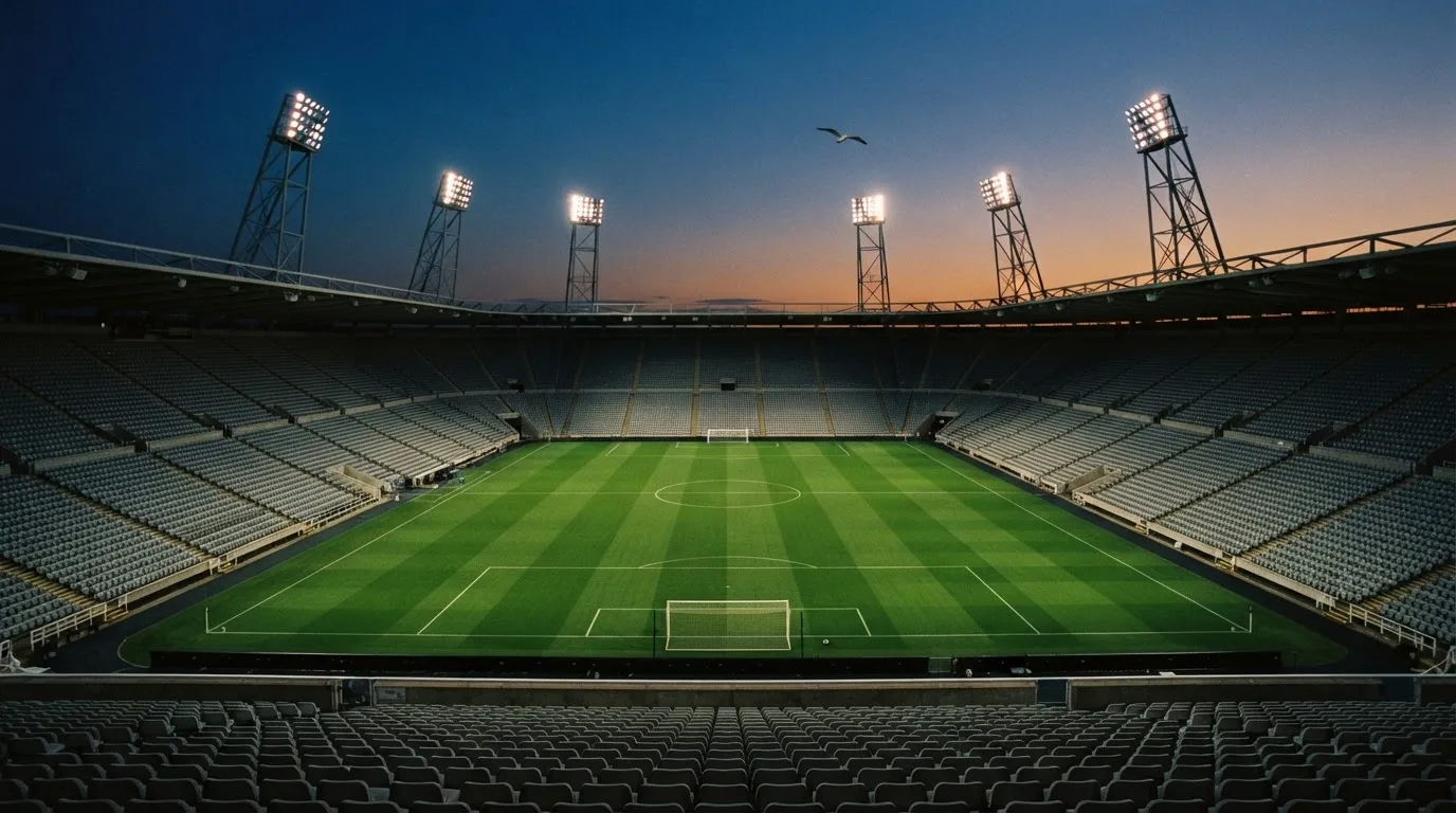 Een leeg voetbalstadion met lichtmasten bij schemering
