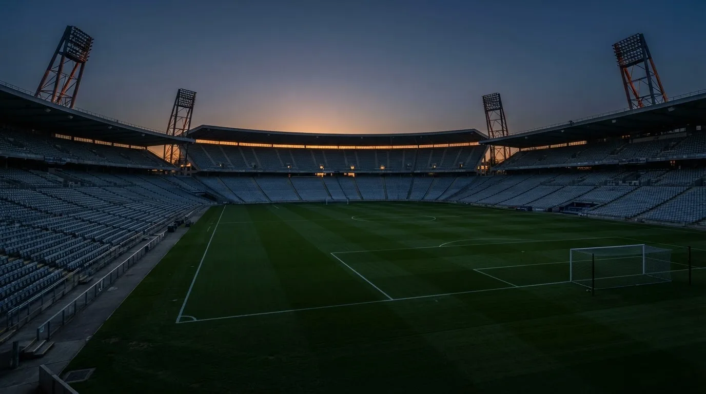 Een leeg voetbalstadion met lichtmasten bij schemering