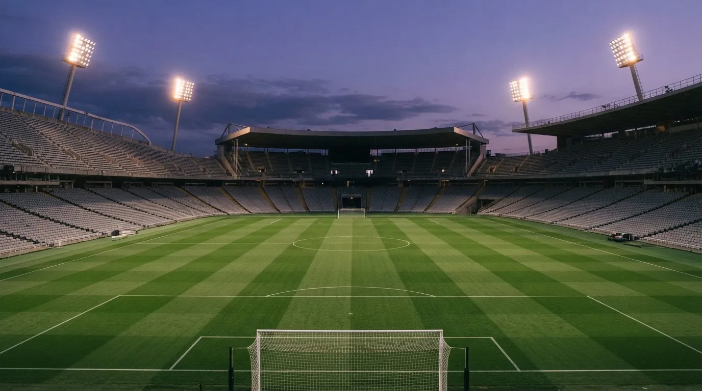 Een leeg voetbalstadion met lichtmasten bij schemering