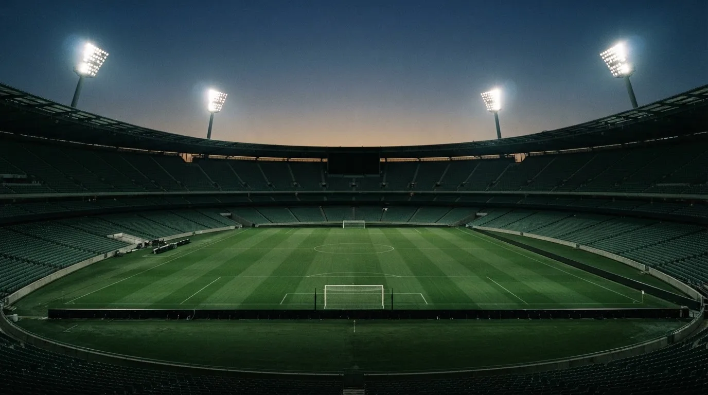 Een leeg voetbalstadion met lichtmasten bij schemering