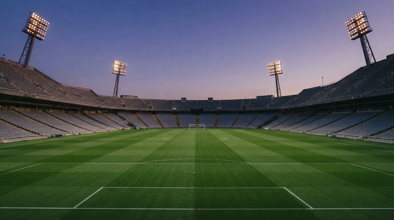 Een leeg voetbalstadion met lichtmasten bij schemering