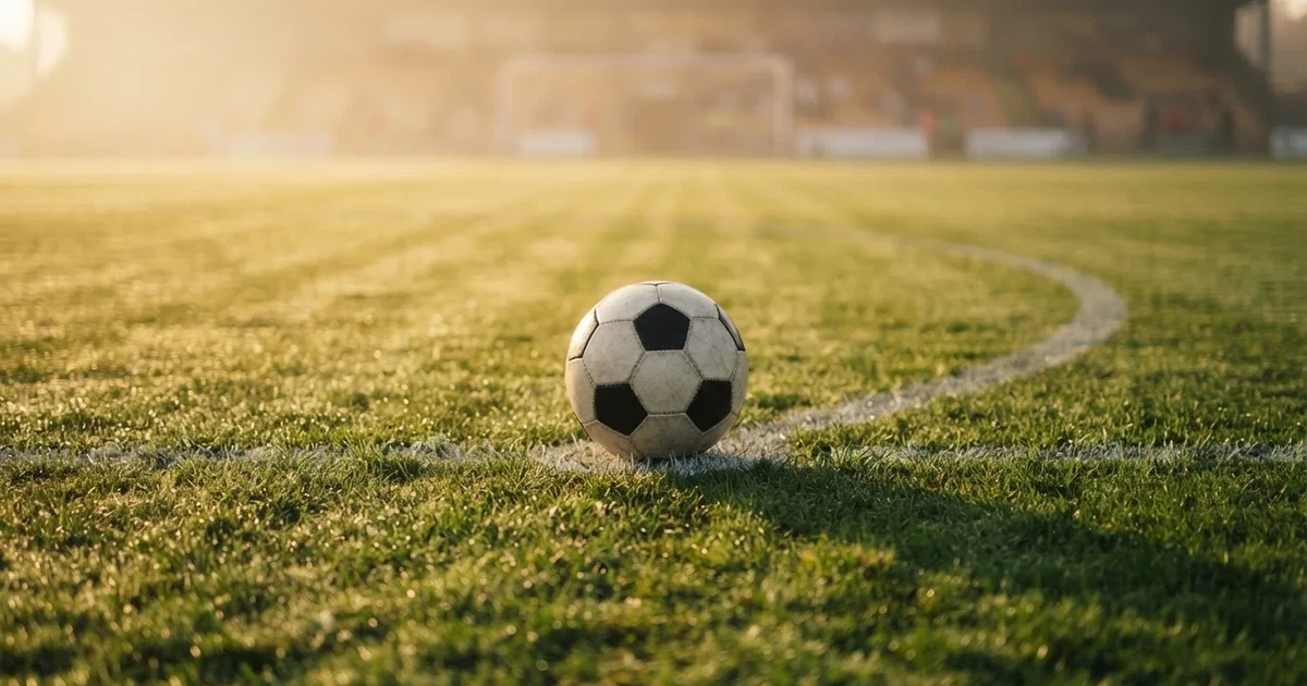 Een voetbal op de middenstip van een grasveld in het ochtendlicht