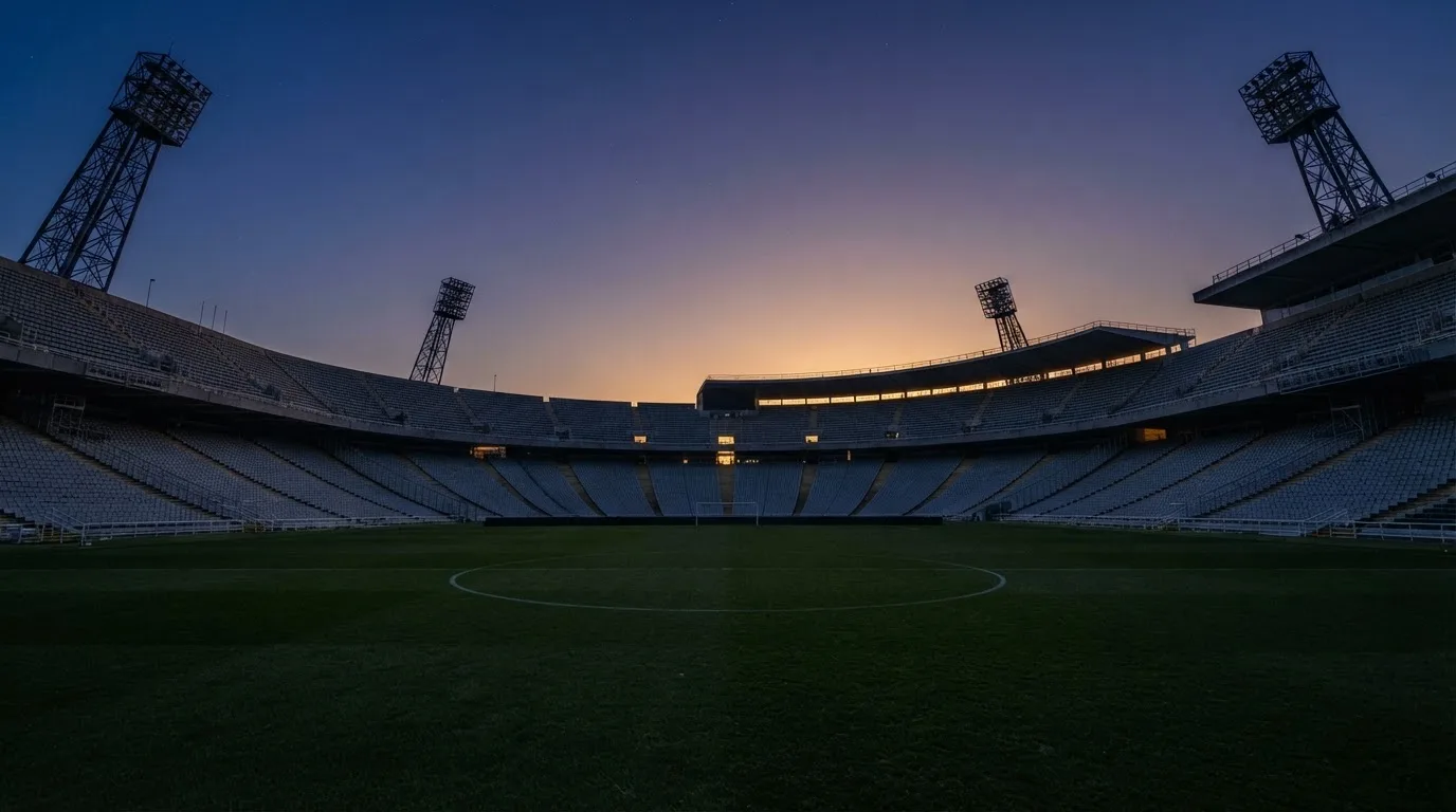 Een leeg voetbalstadion met lichtmasten bij schemering