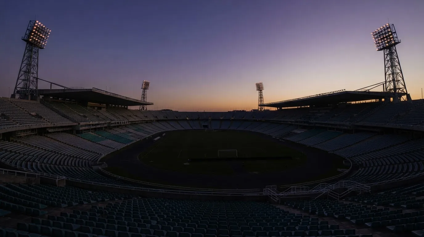 Een leeg voetbalstadion met lichtmasten bij schemering
