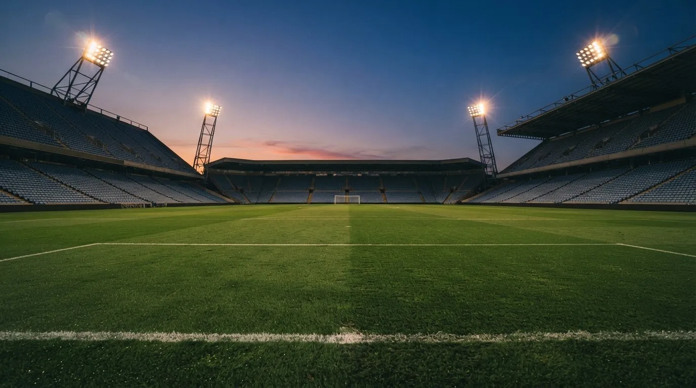 Een leeg voetbalstadion met lichtmasten bij schemering