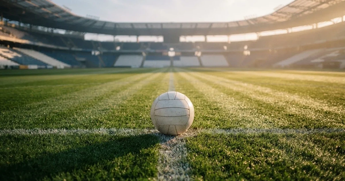 Een voetbal op de middenstip van een grasveld in het ochtendlicht
