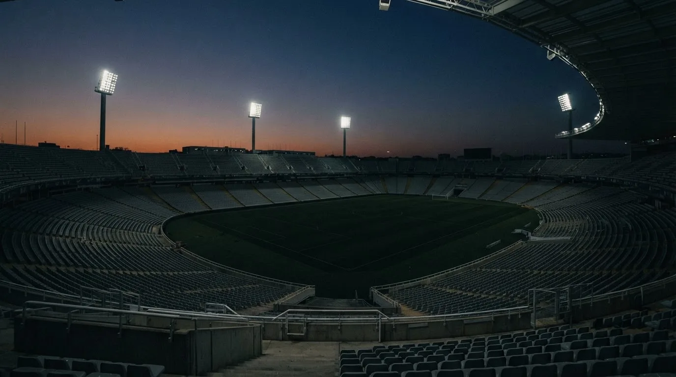 Een leeg voetbalstadion met lichtmasten bij schemering