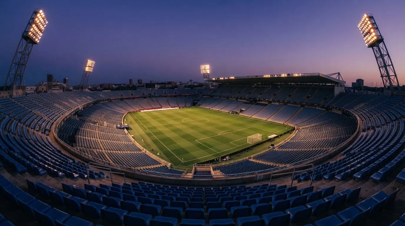 Een leeg voetbalstadion met lichtmasten bij schemering