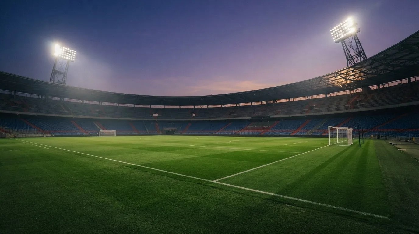 Een leeg voetbalstadion met lichtmasten bij schemering